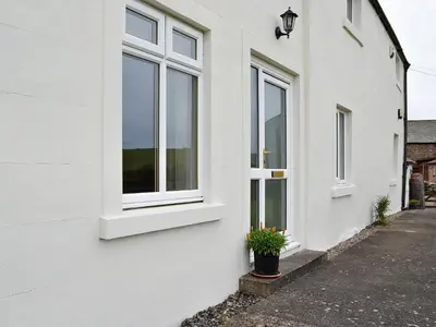 a white house with windows and a potted plant at Farm Cottage in Cleator