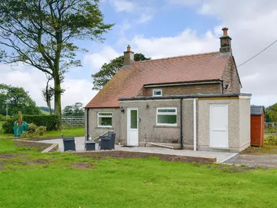 a small house with two white doors and a yard at Rose Cottage in Cleator