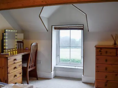 a bedroom with a window and a desk and a dresser at Rose Cottage in Cleator