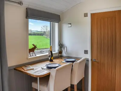 a dining room table with a deer looking out the window at Greengill Farm Shepherds Hut- Ukc3632 in Gilcrux