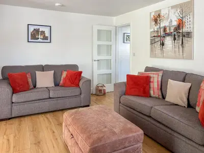 a living room with two gray couches and red pillows at Townend Cottage in Aikton