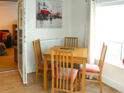 a dining room table with chairs and a mirror at Townend Cottage in Aikton