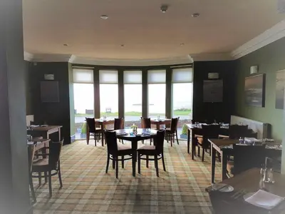 a dining room with tables and chairs and windows at The Powfoot Hotel, Annan in Annan