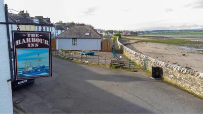 a sign for the harbor inn next to a beach at Harbour Inn Appartments in Garlieston