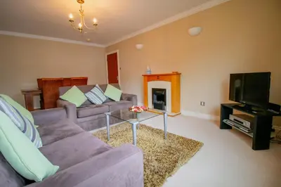 a living room with a couch and a tv at Turnberry Apartments in Turnberry