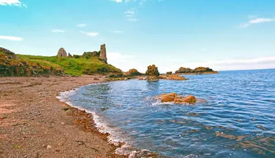 a rocky beach with a castle in the background at Turnberry Apartments in Turnberry