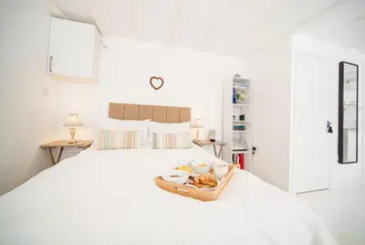 a white bedroom with a bed with a tray of food at The Retreat Studio in Carlisle
