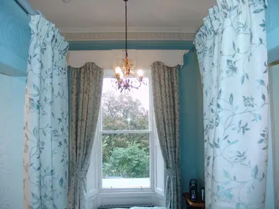 a room with a window with curtains and a chandelier at Osborne House B&B Workington in Workington