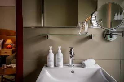 a bathroom sink with a mirror and two bottles on it at Royal Oak at Keswick in Keswick