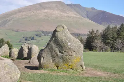 a rock in a field with a mountain in the background at Rooms36 in Keswick