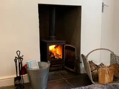 a fireplace in a living room with a bucket at Boggle Dyke Cottage in Thornhill
