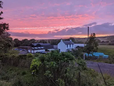 a white house in a field with a sunset at Glen Roe - 3 Bed Lodge on Friendly Farm Stay in New Cumnock