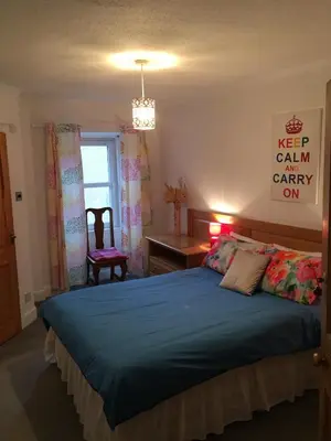 a bedroom with a bed and a desk and a window at Vollie House with Hot Tub, Sauna & Log Burner in Penpont