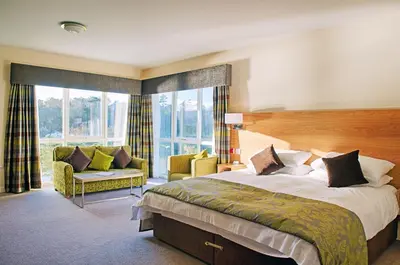 a bedroom with a bed and a couch and windows at Ramsey Park Hotel in Ramsey