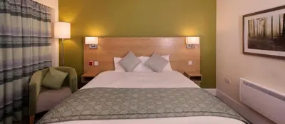 a hotel room with a bed and a chair at Ramsey Park Hotel in Ramsey