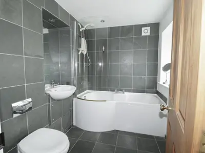 a bathroom with a tub and a toilet and a sink at Holemire Barn in Cockermouth