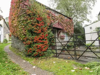 a ivy covered building with a gate and flowers at Holemire Barn in Cockermouth