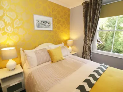 a bedroom with a bed with yellow walls and a window at Shepherd's Crook in Ambleside