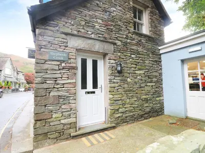 a stone building with a white door on a street at Shepherd's Crook in Ambleside