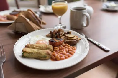 a plate of breakfast food with eggs beans and a glass of orange juice at Pinegrove Hotel in Carlisle