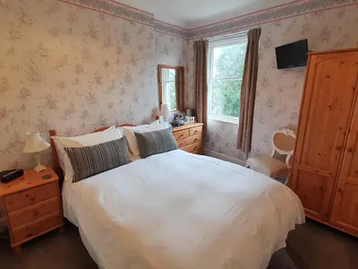 a bedroom with a large white bed and a window at Strathmore Guest House in Keswick