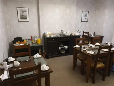 a dining room with tables and chairs and a kitchen at Strathmore Guest House in Keswick