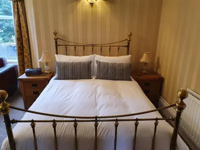 a bedroom with a large bed with white sheets and pillows at Strathmore Guest House in Keswick