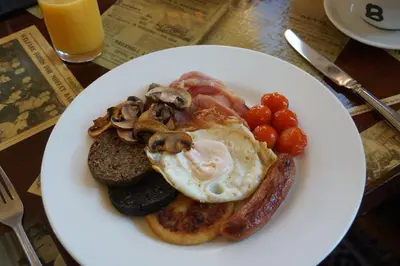 a plate of breakfast food with eggs sausage and mushrooms at Buccleuch Arms Hotel in Moffat