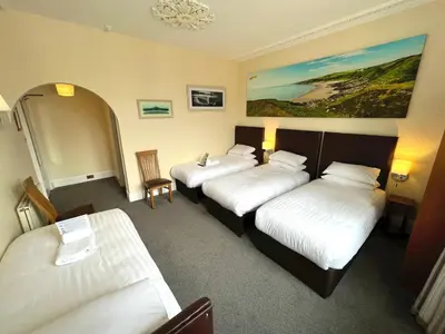 a hotel room with three beds and a couch at Buccleuch Arms Hotel in Moffat