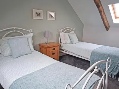 a bedroom with two beds and a night stand with a lamp at Swallow Barn in Torpenhow