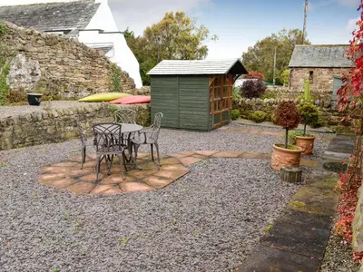 a patio with a table and chairs and a shed at Swallow Barn in Torpenhow
