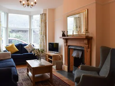a living room with a blue couch and a fireplace at Otterbield in Keswick