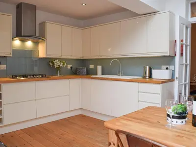 a kitchen with white cabinets and a wooden table at Otterbield in Keswick