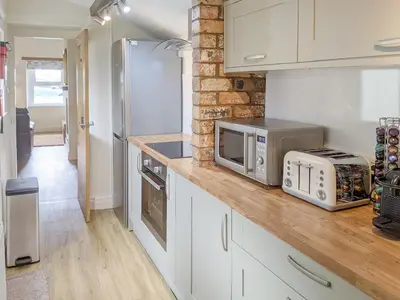 a kitchen with a counter with a microwave and a refrigerator at Seascape Cottage in Allonby