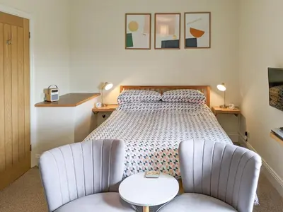 a bedroom with a bed and two chairs at Seascape Cottage in Allonby