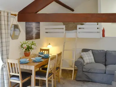a dining room with a table and chairs and a bunk bed at Barn Owl Bothy in Westward