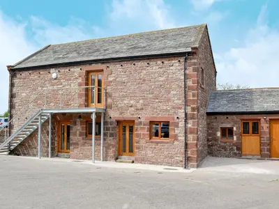 an old brick building with orange doors and windows at The Byres Tan in St Bees