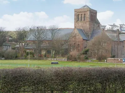 a large brick building with a tower and a church at The Byres Tan in St Bees