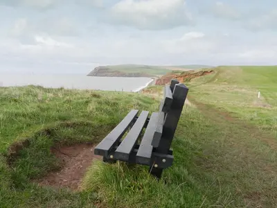 a black bench sitting on a hill overlooking the ocean at The Byres Tethera in St Bees