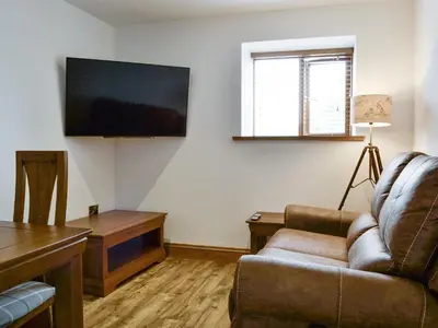 a living room with a couch and a flat screen tv at The Byres Methera in St Bees