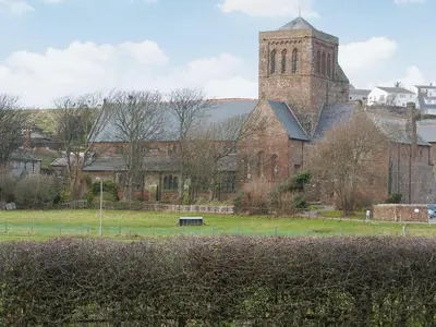a large brick building with a tower and a church at The Byres Methera in St Bees