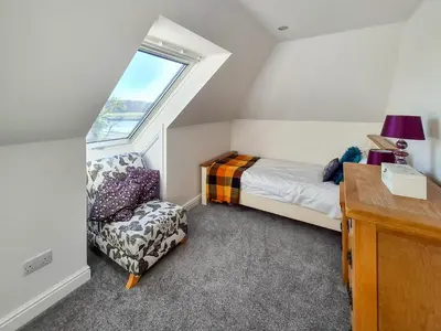 a small bedroom with a bed and a chair at Gullsway in Glencaple