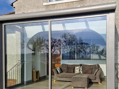 a couch is sitting inside of a glass window at Gullsway in Glencaple