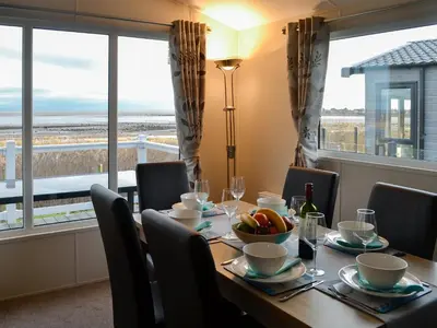 a dining room with a table with chairs and a window at Beachcomber Lodge in Mainsriddle