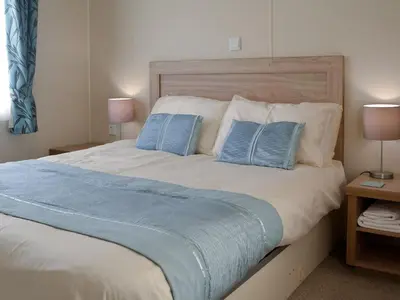 a large bed with two blue pillows on it at Beachcomber Lodge in Mainsriddle