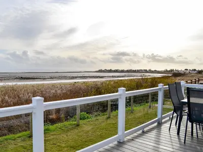a deck with a table and chairs on the beach at Beachcomber Lodge in Mainsriddle