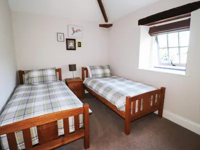 a bedroom with two beds and a window at Carleton Mill Cottage in Carlisle