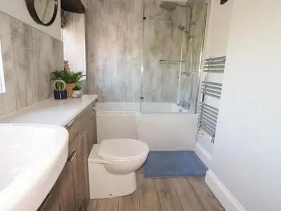 a bathroom with a toilet and a tub and a shower at Carleton Mill Cottage in Carlisle