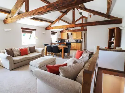 a living room with couches and a dining room at Carleton Mill Cottage in Carlisle