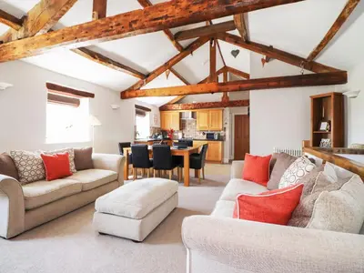 a living room with wooden ceilings and a dining room at Carleton Mill Cottage in Carlisle